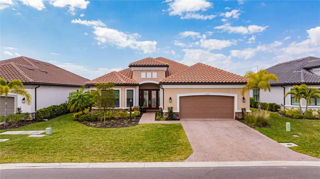 A single-story house with a tile roof, beige stucco exterior, and a paved driveway — 17602 TERRACINA DRIVE, FORT MYERS, FL