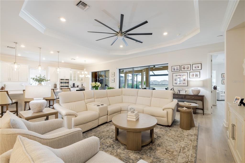 A spacious open-concept living room features a large white sectional, round coffee table, and kitchen — 17602 TERRACINA DRIVE, FORT MYERS, FL