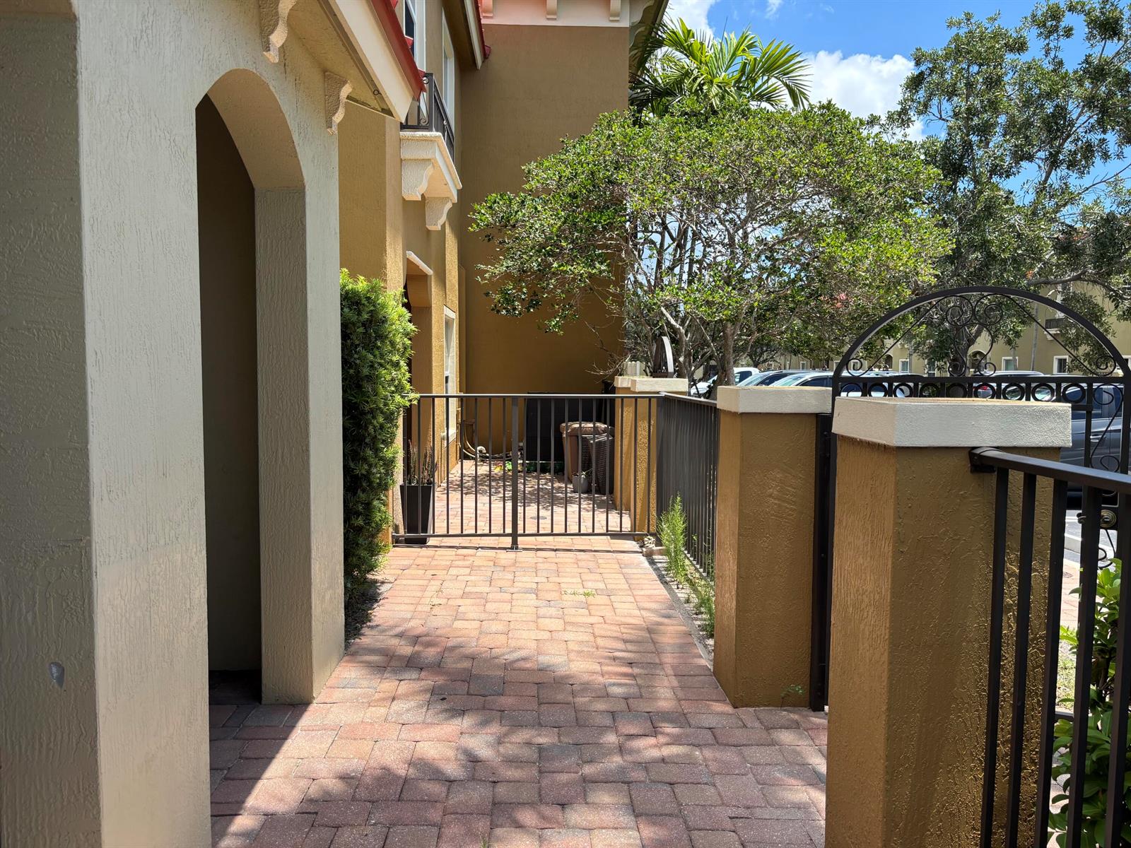 A paved walkway leads to a gated entrance beside a tan building with arched architecture — 161 Monterey Bay Drive, Boynton Beach FL 33426, BOYNTON BEACH, FL
