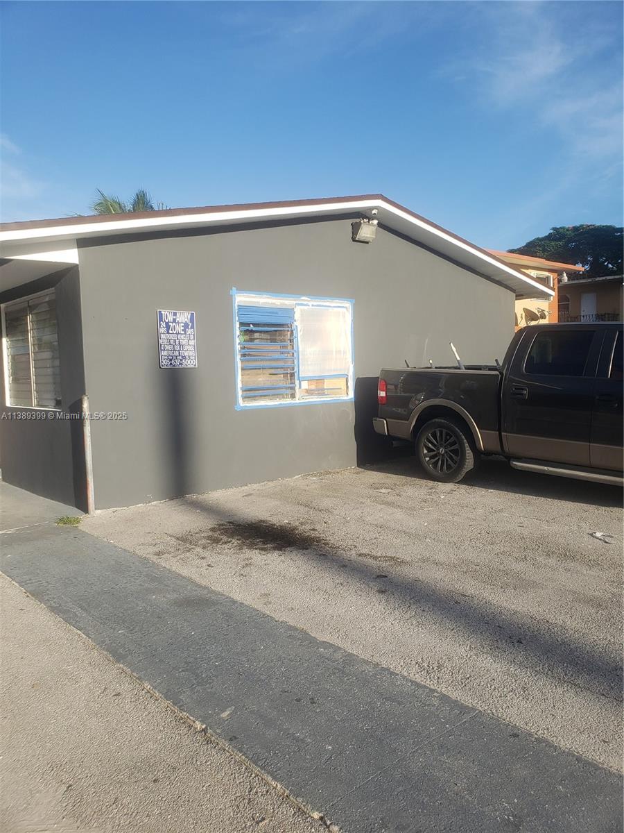 A dark gray exterior wall features a window with blue tape and a tow-away sign — 2855 NW 22nd Ave, Miami FL 33142, MIAMI, FL