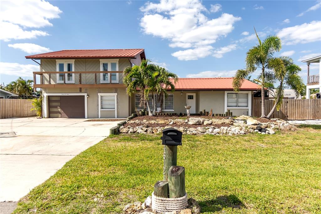 A two-story house with a metal roof, a balcony, and a front yard with palm trees — 4612 7TH STREET COURT E, ELLENTON, FL