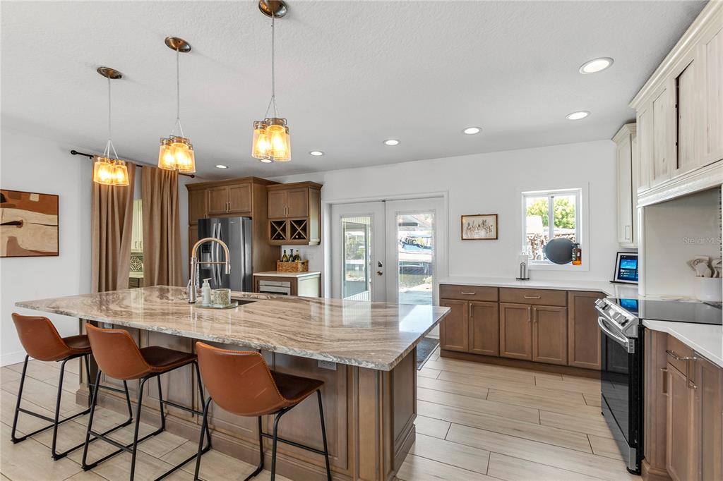 A kitchen features a large stone-topped island, brown cabinetry, and three pendant lights — 4612 7TH STREET COURT E, ELLENTON, FL