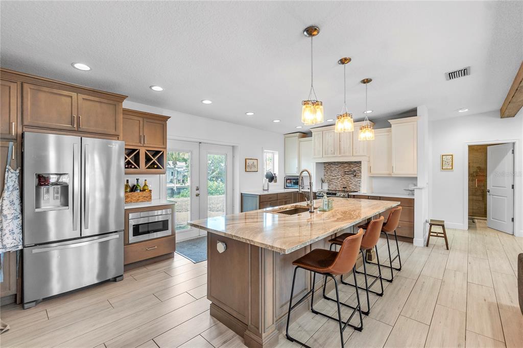 A kitchen features a large granite island, stainless steel appliances, and wood-toned cabinetry — 4612 7TH STREET COURT E, ELLENTON, FL
