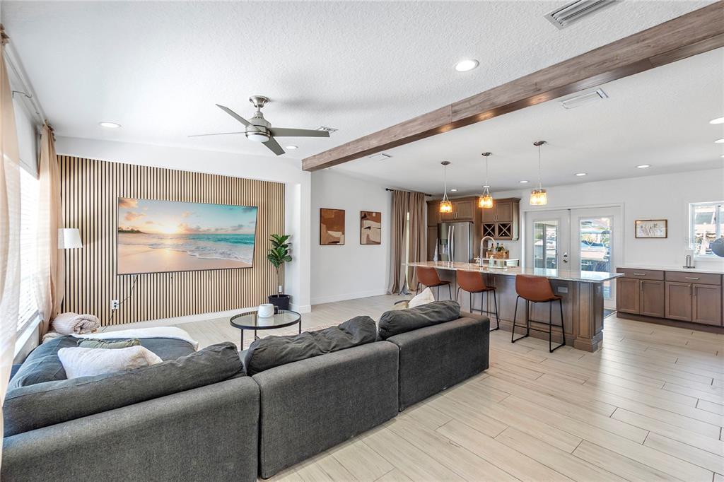 An open-concept living room and kitchen feature a slatted wood accent wall and ceiling beam — 4612 7TH STREET COURT E, ELLENTON, FL