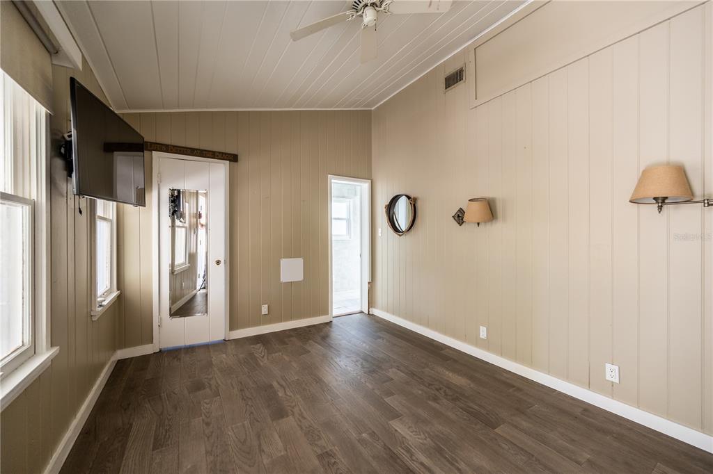 A room with light-colored wood-paneled walls, dark wood-look flooring, and a ceiling fan — 115 124TH AVENUE W, TREASURE ISLAND, FL