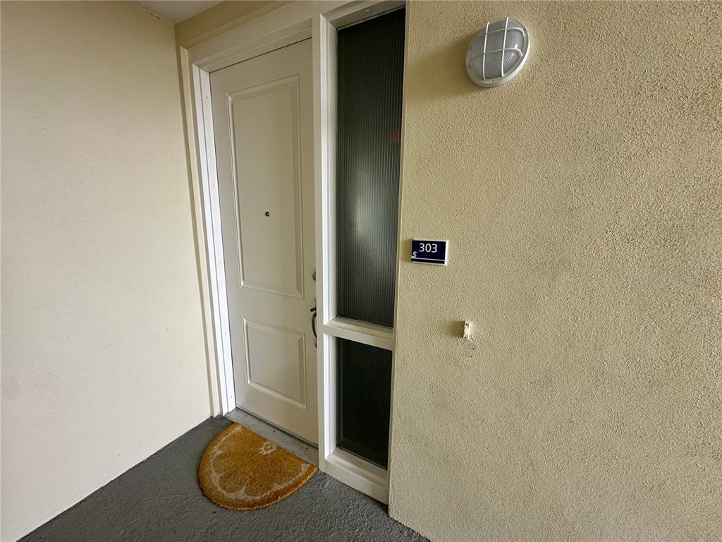 A white door with a side window and a unit number sign on a wall — 3426 W 79 STREET W UNIT 303, BRADENTON, FL