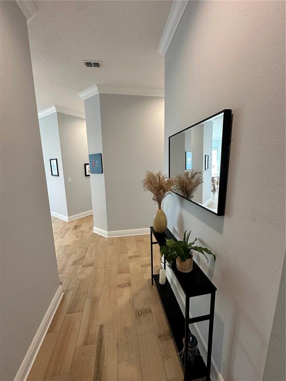 A hallway features light wood-look tile flooring, gray walls, and a black console table with decor — 3426 W 79 STREET W UNIT 303, BRADENTON, FL