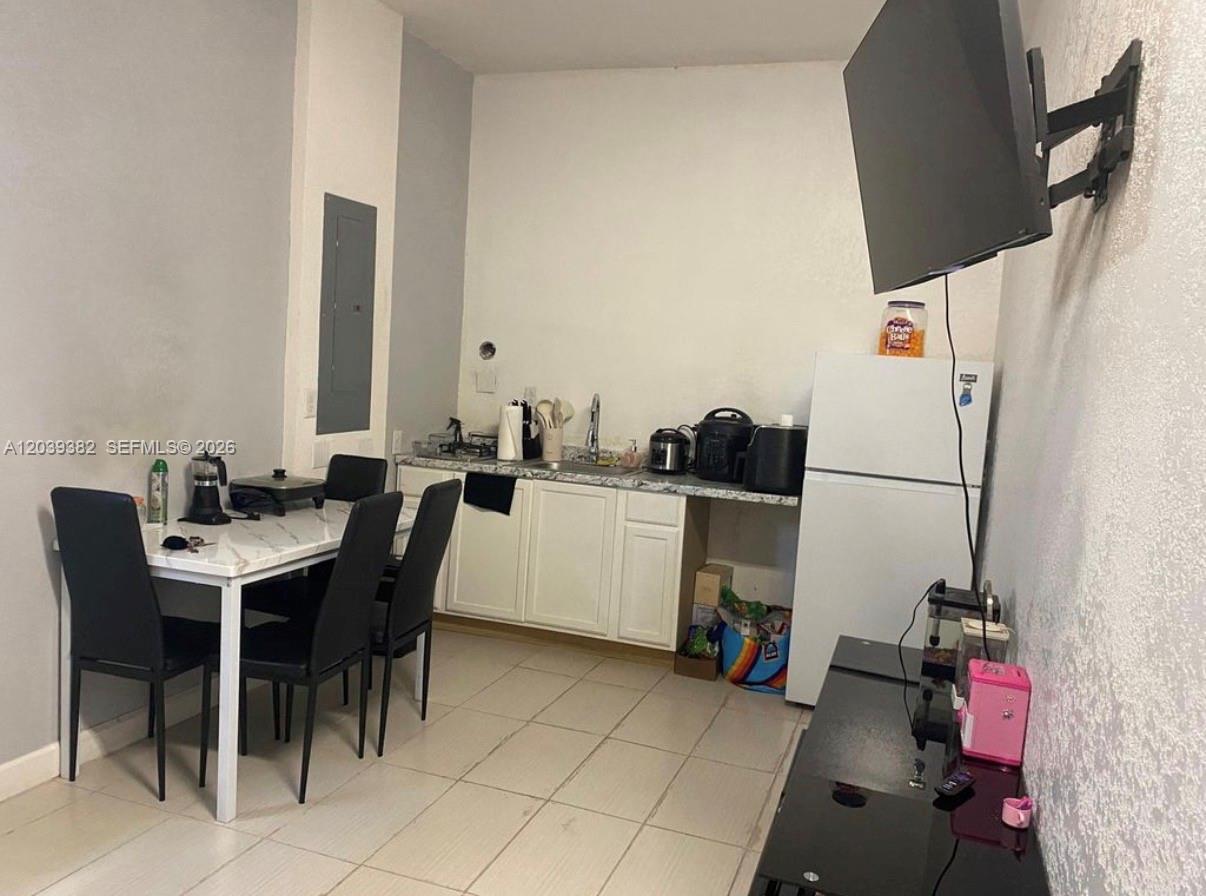 A kitchen area features white cabinets, a dining table with chairs, and a refrigerator — HOMESTEAD, FL