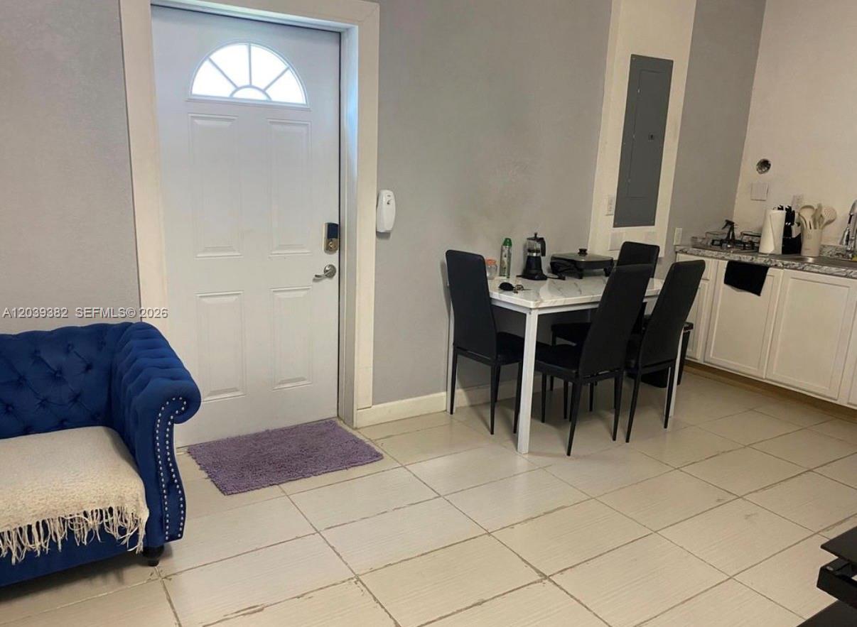 A room features a blue tufted sofa, a dining table with four chairs, and kitchen cabinets — HOMESTEAD, FL