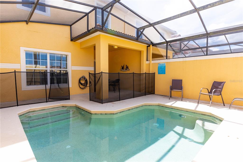 A screened-in patio features a swimming pool, a covered seating area, and yellow exterior walls — 8873 CANDY PALM ROAD, KISSIMMEE, FL