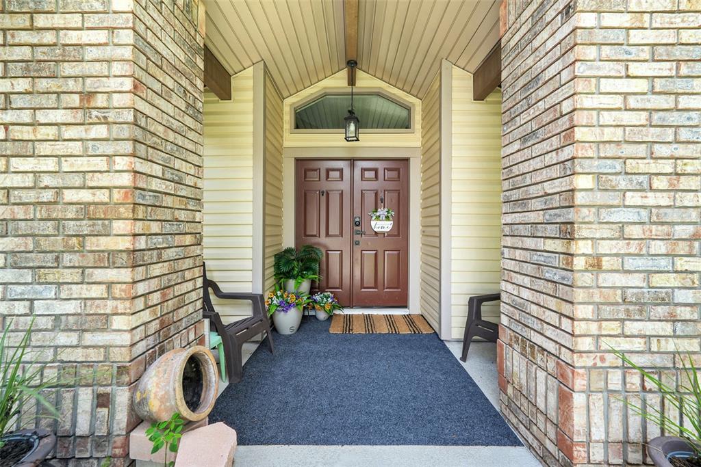 A covered entryway features a double brown door, brick columns, and a gray floor mat — 305 FORREST CREST COURT, OCOEE, FL