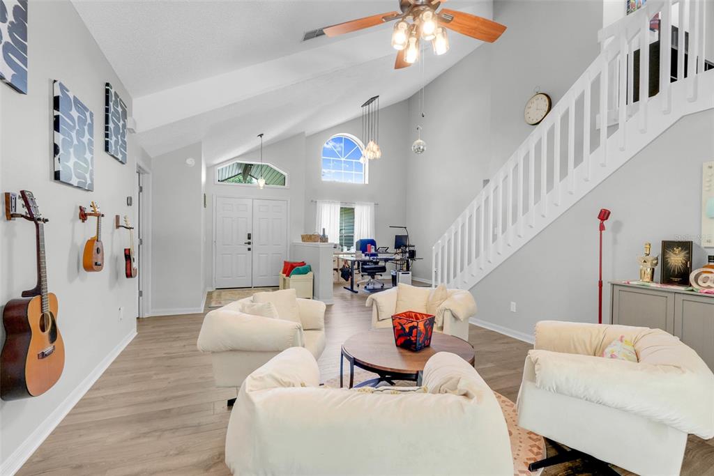 A living room with vaulted ceilings, white walls, light wood flooring, and a staircase — 305 FORREST CREST COURT, OCOEE, FL