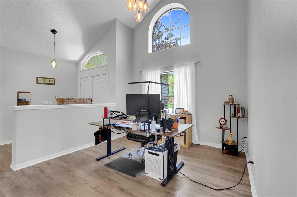 A home office with a standing desk, wood-look flooring, and a high vaulted ceiling — 305 FORREST CREST COURT, OCOEE, FL