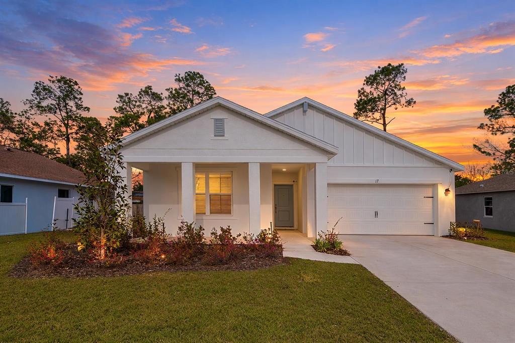 A single-story white house with a two-car garage and a front porch at sunset — 17 BIRCHWOOD PLACE, PALM COAST, FL