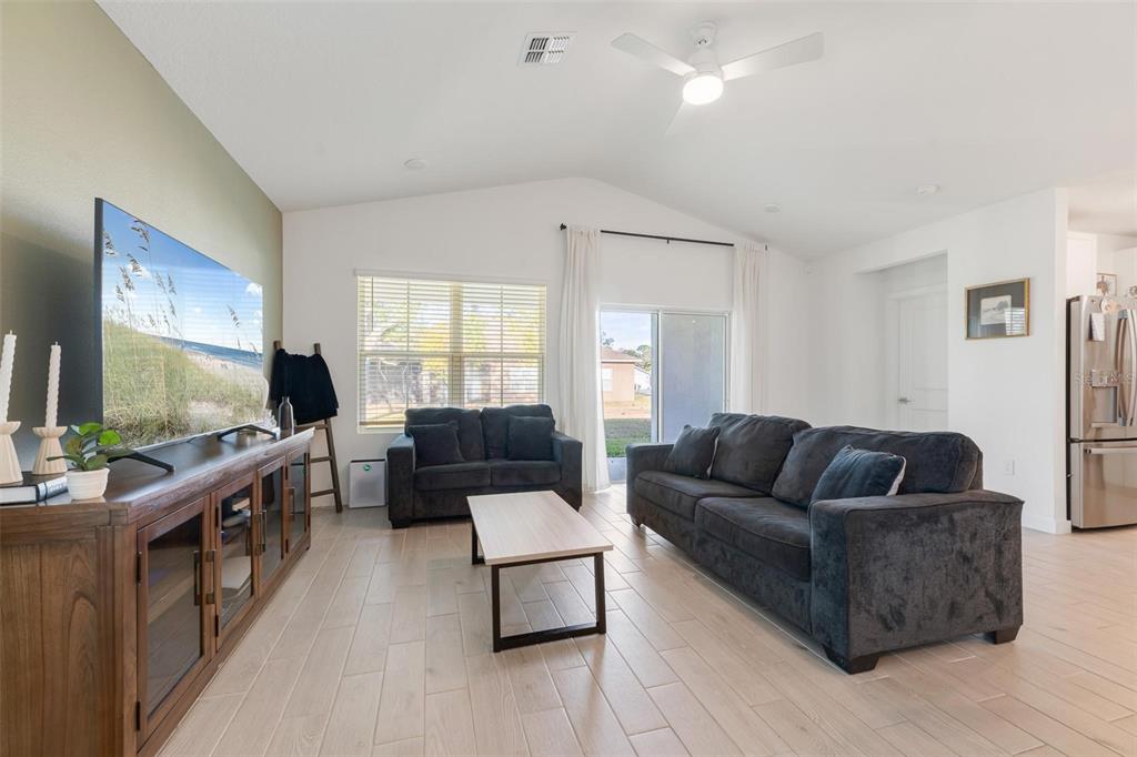 A living room features light tile floors, a vaulted ceiling, and dark gray upholstered furniture — 17 BIRCHWOOD PLACE, PALM COAST, FL