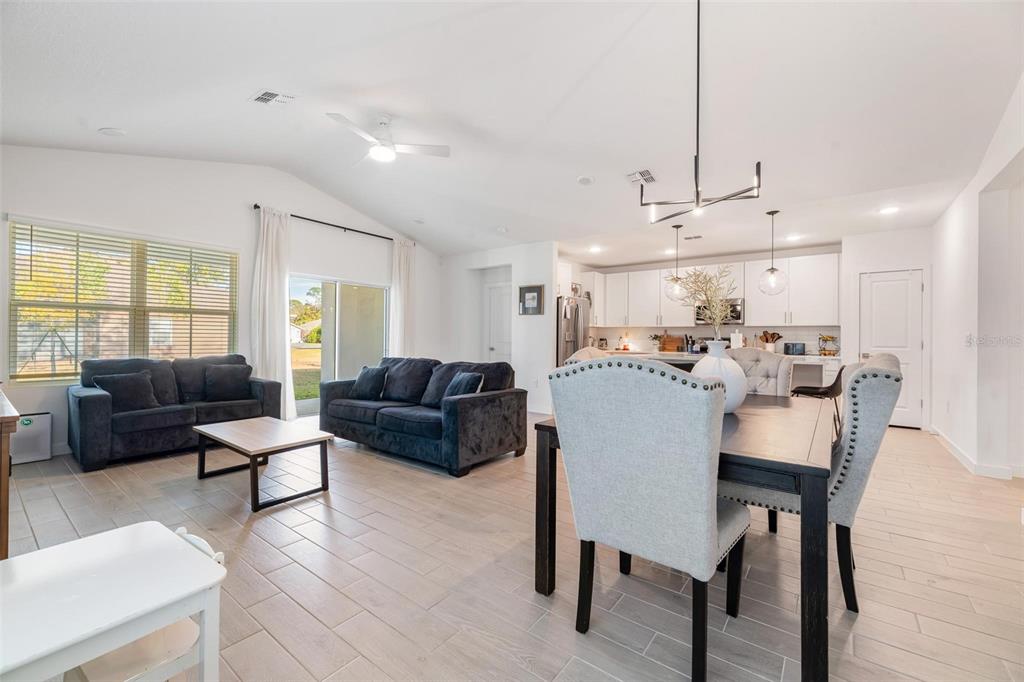 An open-concept living and dining area features light tile flooring, white cabinetry, and dark furniture — 17 BIRCHWOOD PLACE, PALM COAST, FL