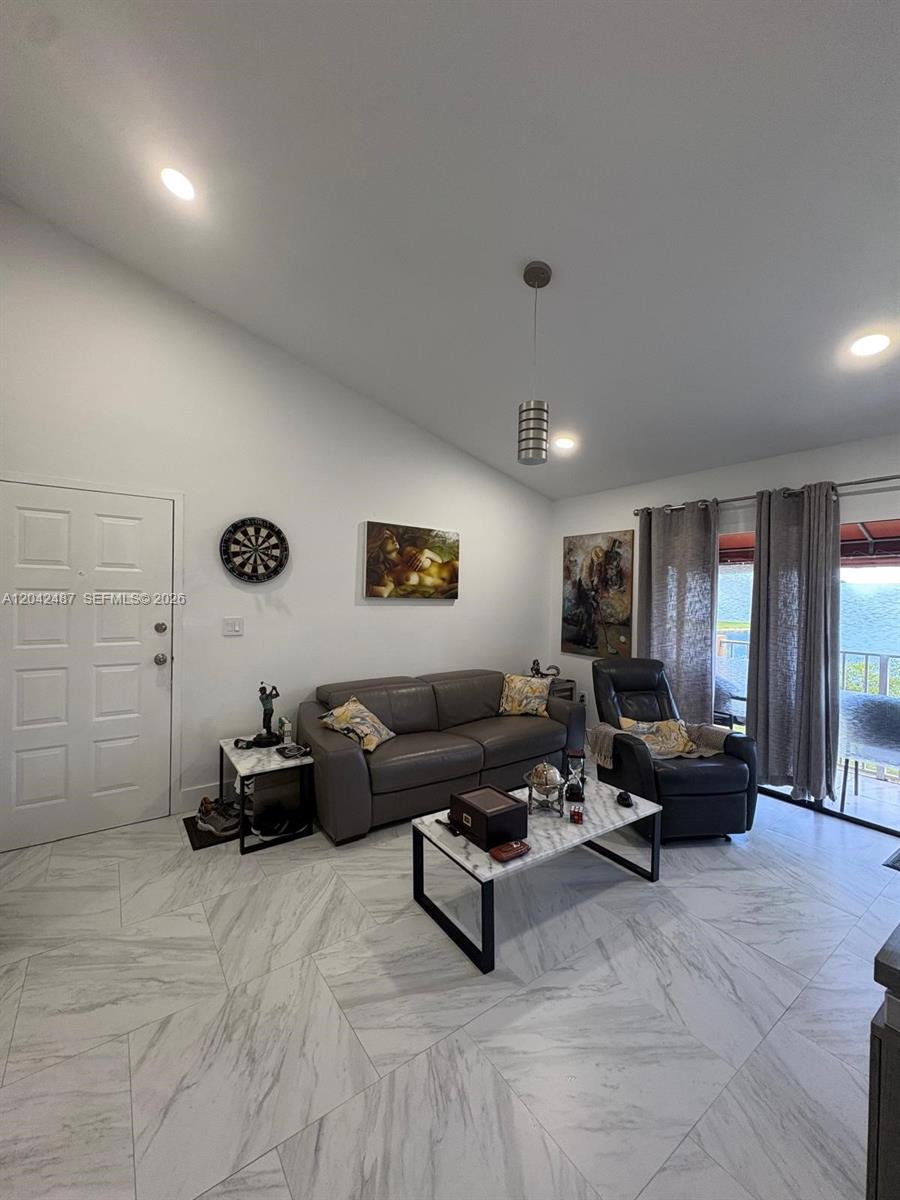 A living room features gray tile flooring, a leather sofa, a recliner, and a sliding door — 15560 SW 80th St # 205, Miami FL 33193, MIAMI, FL
