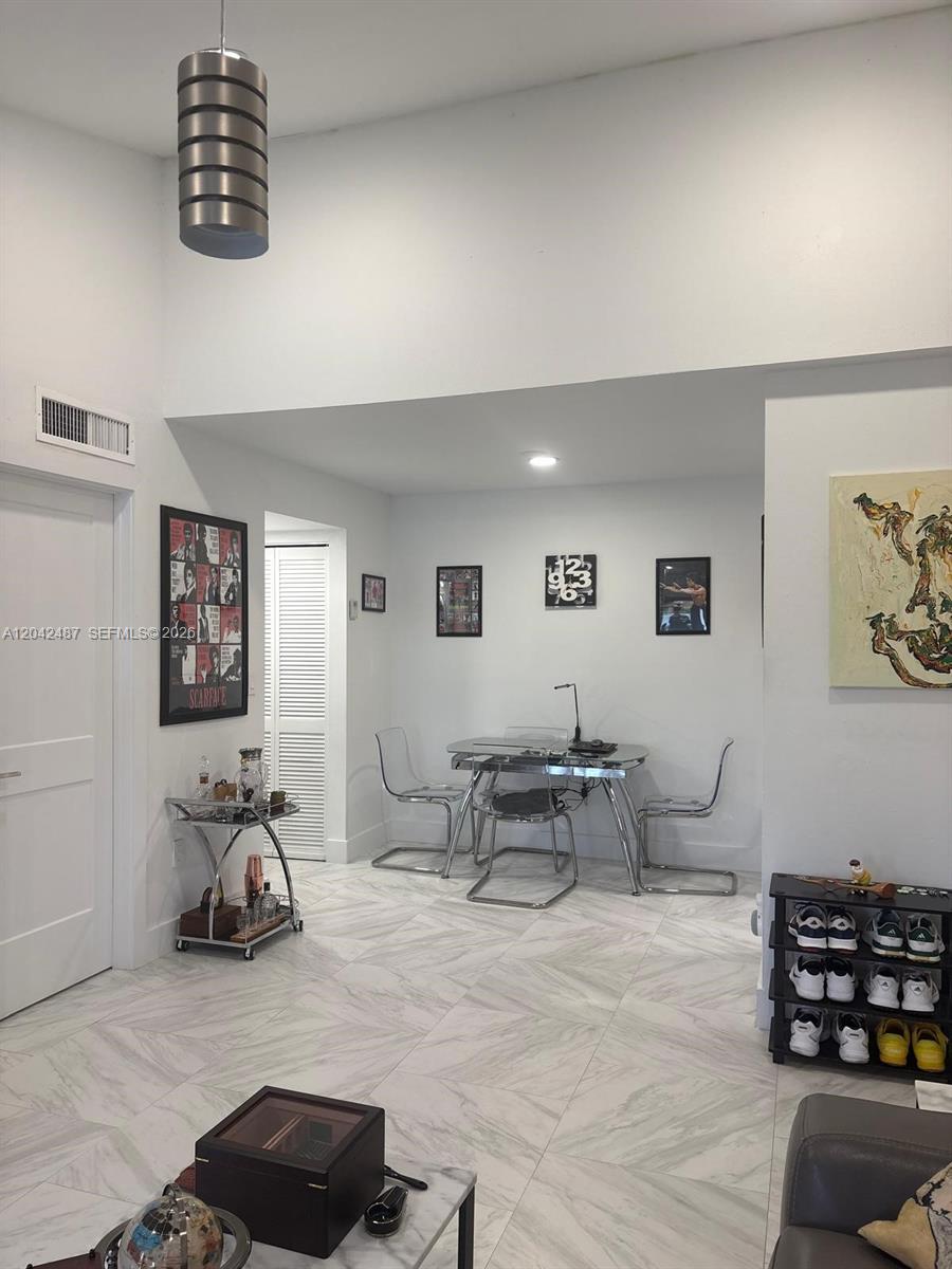 A dining area features a glass table, clear chairs, a bar cart, and tiled floors — 15560 SW 80th St # 205, Miami FL 33193, MIAMI, FL