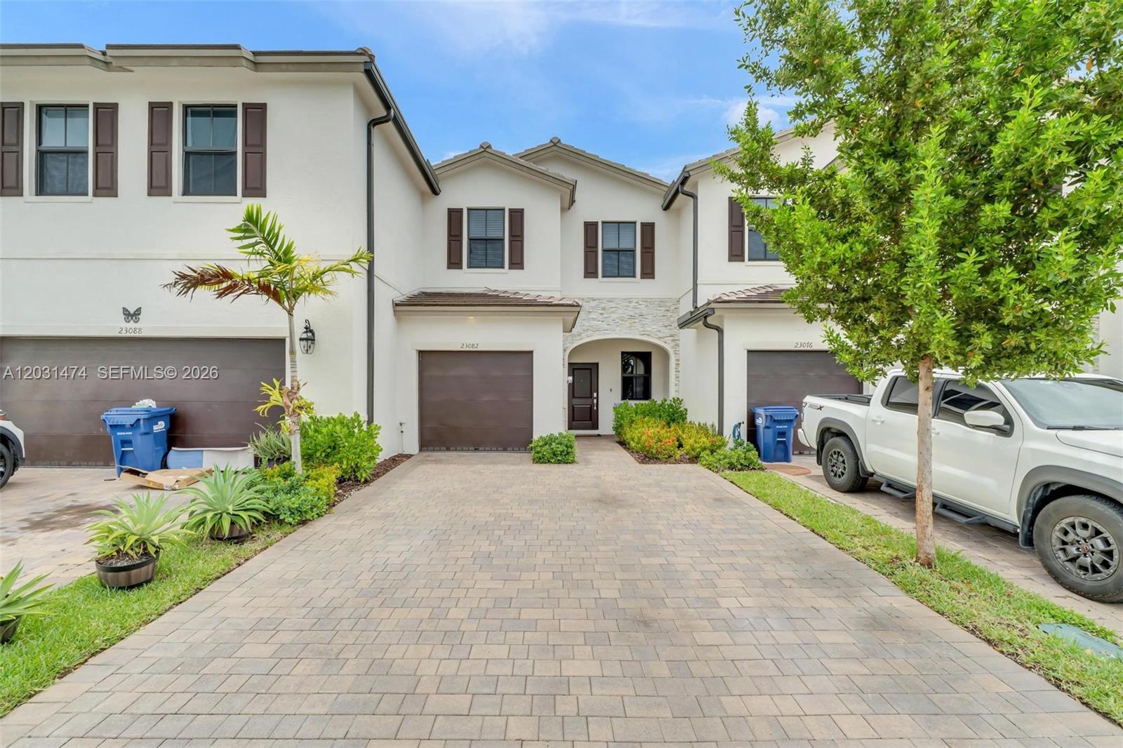 A row of three two-story townhouses with paved driveways and attached garages — 23082 SW 129th Ct, Miami FL 33170, MIAMI, FL