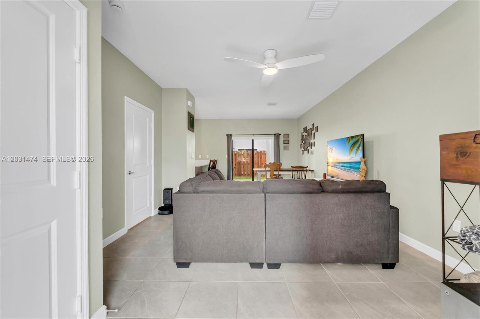 A living room features a large gray sectional sofa, tile flooring, and a sliding glass door — 23082 SW 129th Ct, Miami FL 33170, MIAMI, FL