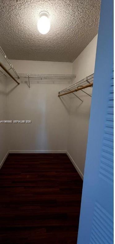 A walk-in closet features white walls, wire shelving, and dark wood-look flooring — 18965 NW 62nd Ave # 202, Hialeah FL 33015, HIALEAH, FL