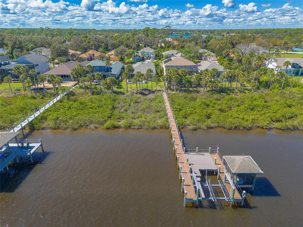 An aerial view shows houses along a waterfront with two long wooden boat docks — 31 S RIVERWALK DRIVE, PALM COAST, FL