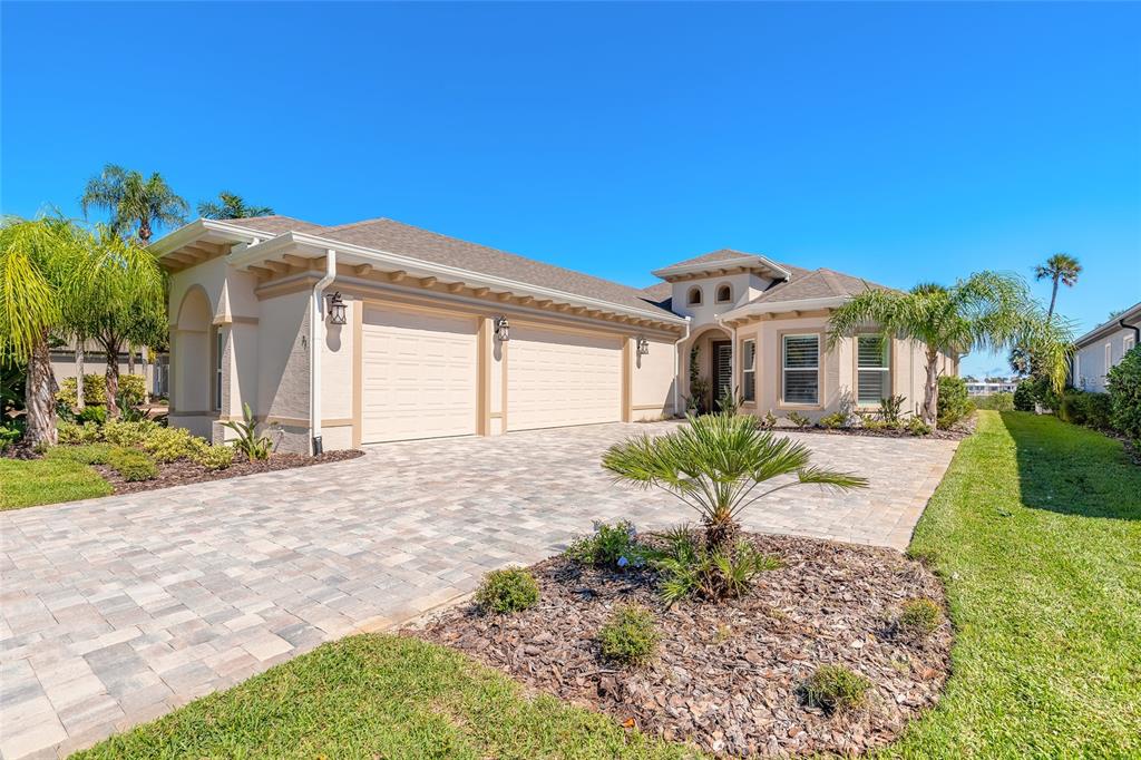 A single-story house with a beige stucco exterior, a paver driveway, and a three-car garage — 31 S RIVERWALK DRIVE, PALM COAST, FL