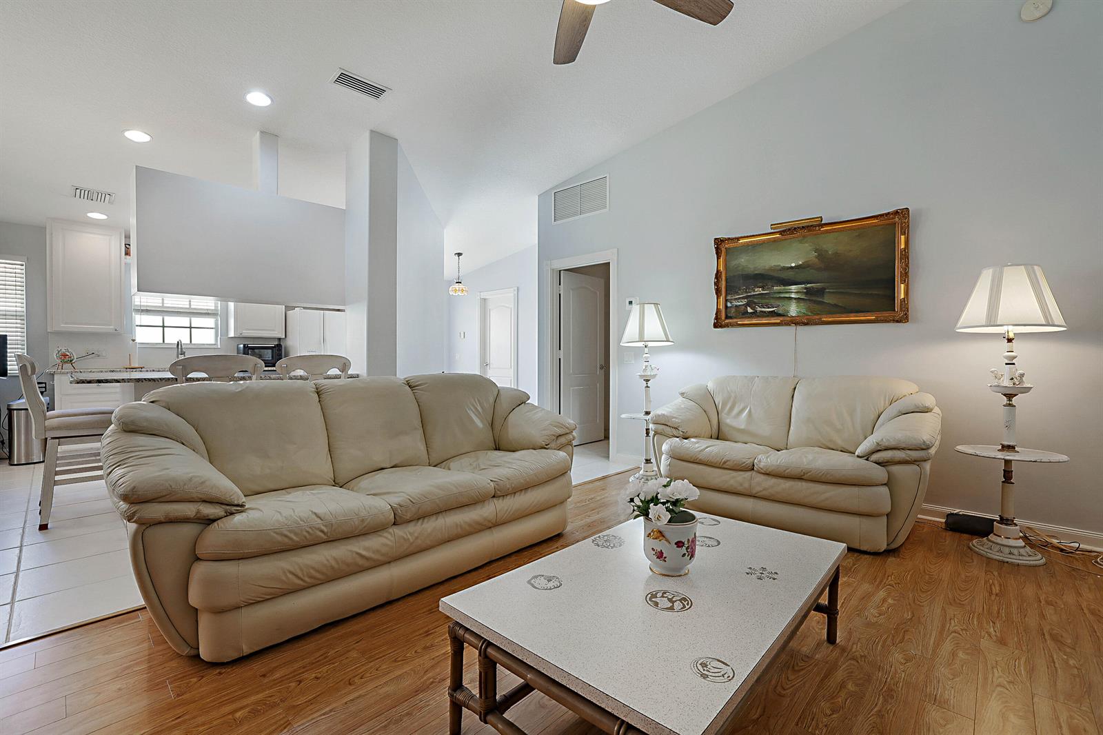 A living room features two cream leather sofas, a coffee table, and light wood flooring — 774 SW Balmoral Trace, Stuart FL 34997, STUART, FL