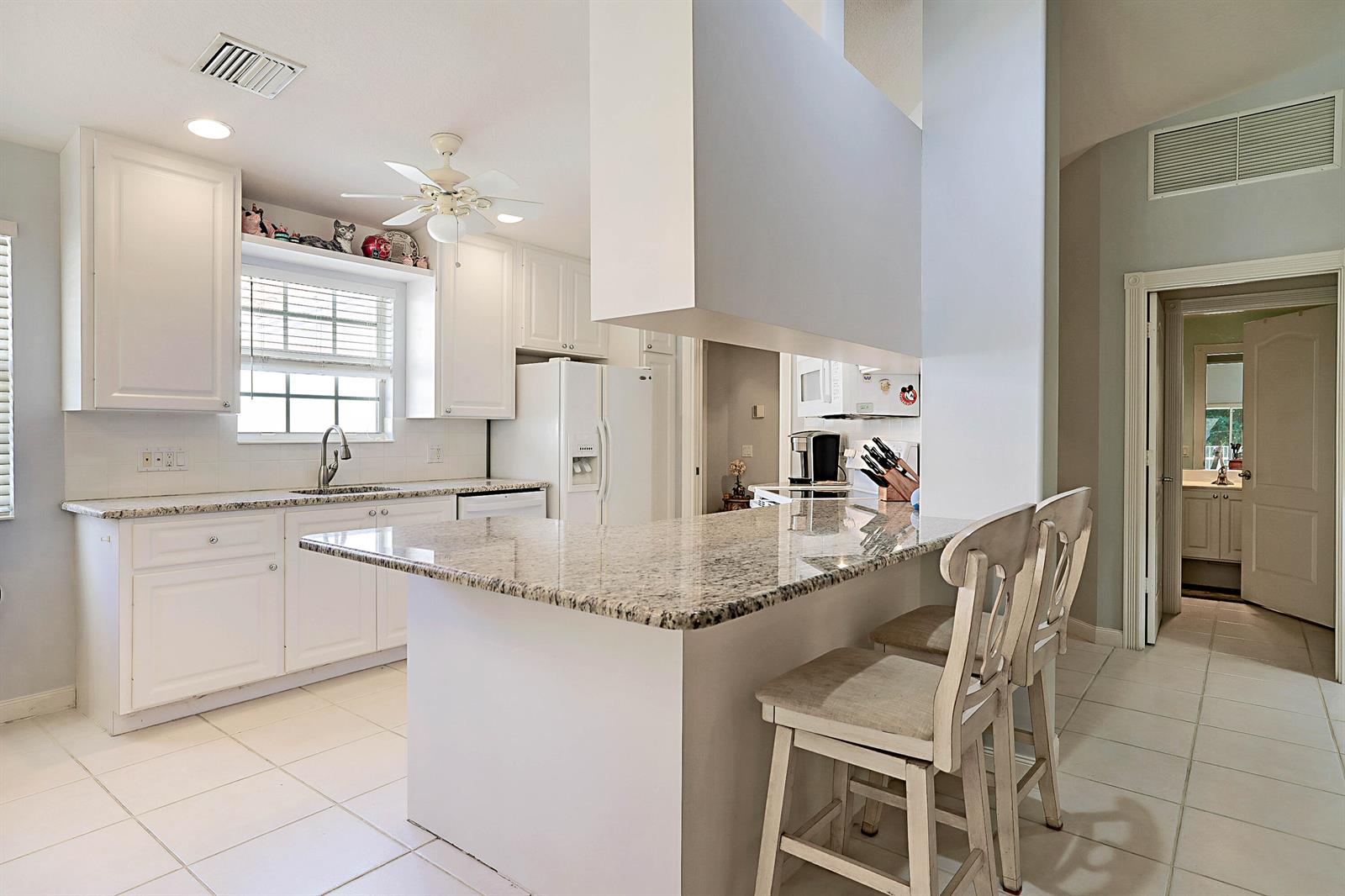A kitchen features white cabinets, granite countertops, a breakfast bar, and tile flooring — 774 SW Balmoral Trace, Stuart FL 34997, STUART, FL