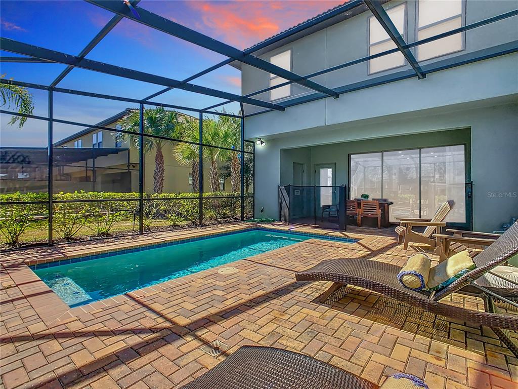 A screened-in patio features a rectangular swimming pool, brick pavers, and lounge chairs — 4594 TERRASONESTA DRIVE, DAVENPORT, FL