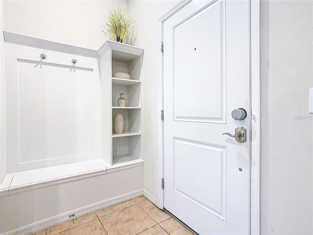 An entryway features a white built-in bench with coat hooks, open shelving, and a door — 4594 TERRASONESTA DRIVE, DAVENPORT, FL