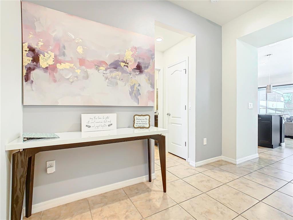 A hallway features a white console table, abstract wall art, and tile flooring — 4594 TERRASONESTA DRIVE, DAVENPORT, FL