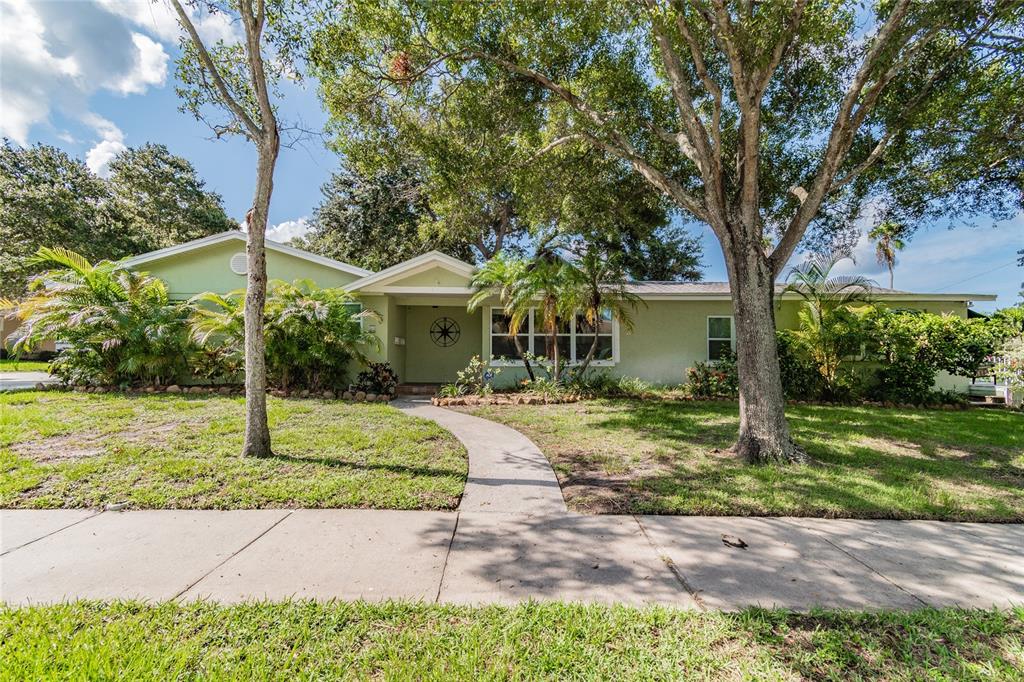 A single-story light green house with a front walkway, mature trees, and landscaping — 303 WILDWOOD WAY UNIT A, CLEARWATER, FL