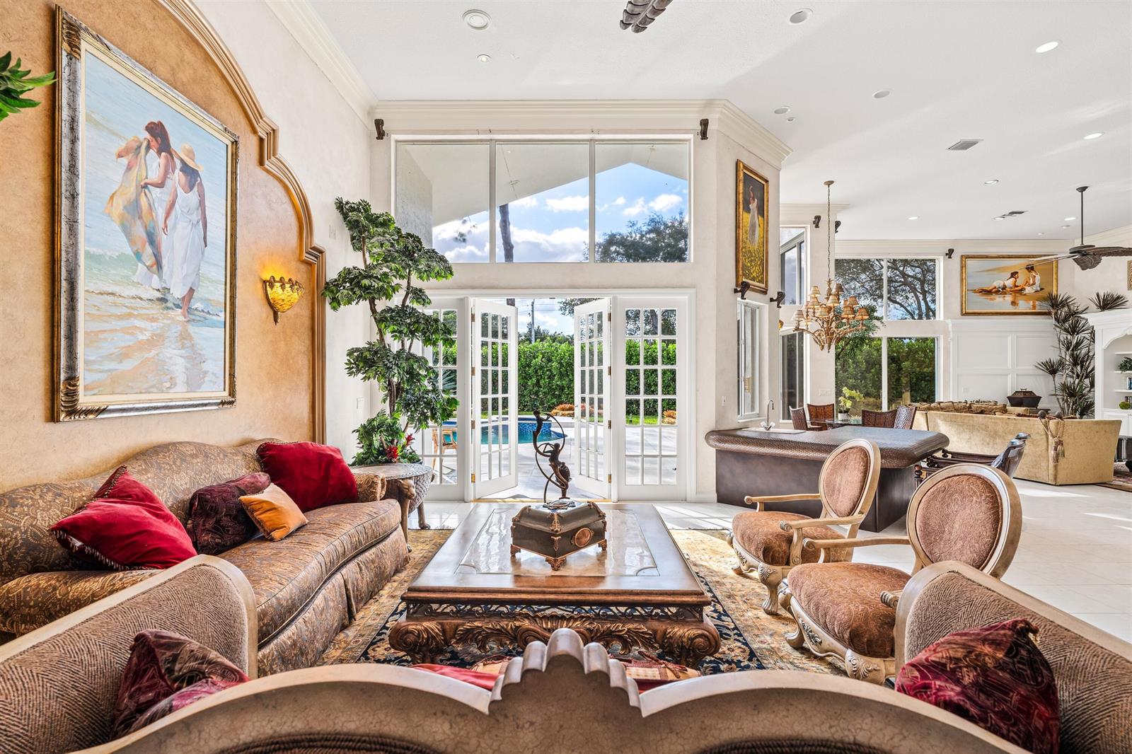 A spacious living room features ornate furniture, a large painting, and glass doors opening outdoors — 4475 NW 24th Terrace, Boca Raton FL 33431, BOCA RATON, FL