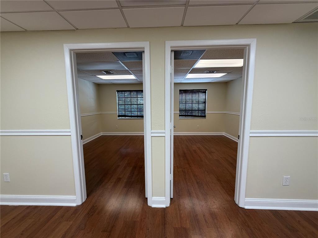 Two identical office rooms with wood-look flooring and windows are visible through two doorways — 4828 W GANDY BOULEVARD UNIT B27, TAMPA, FL