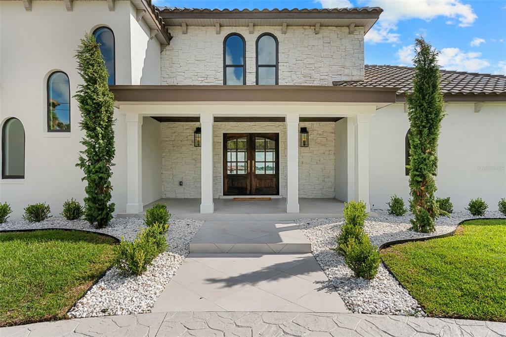 A white stucco and stone house features a covered entryway with double wooden doors — 2501 TRENTWOOD BOULEVARD, ORLANDO, FL