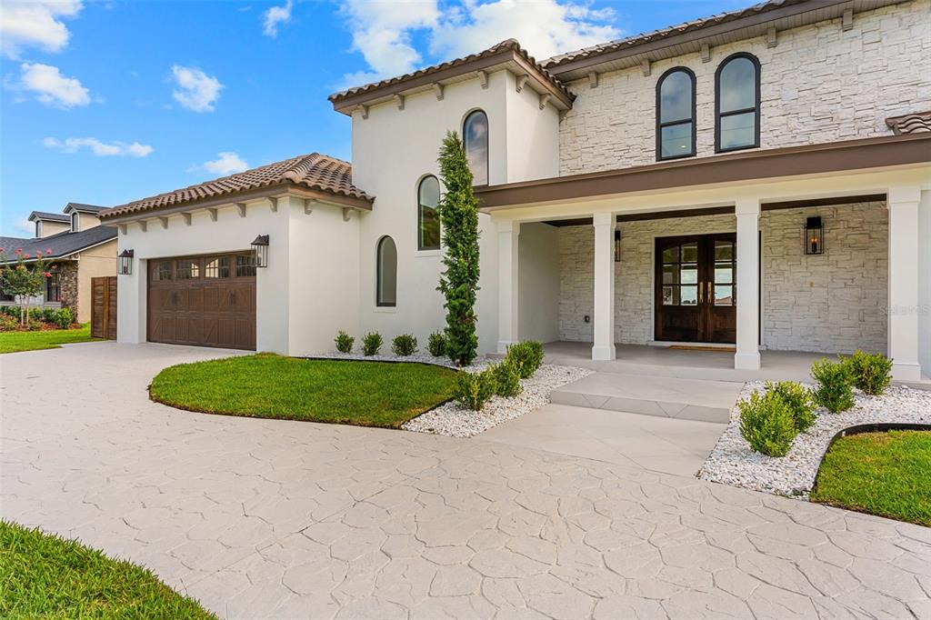 A modern two-story house features a stone facade, arched windows, and a stamped concrete driveway — 2501 TRENTWOOD BOULEVARD, ORLANDO, FL