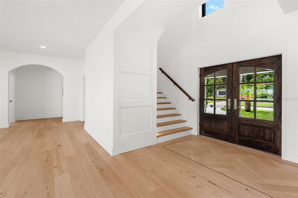 A bright foyer features light wood flooring, a dark wood double door, and a staircase — 2501 TRENTWOOD BOULEVARD, ORLANDO, FL