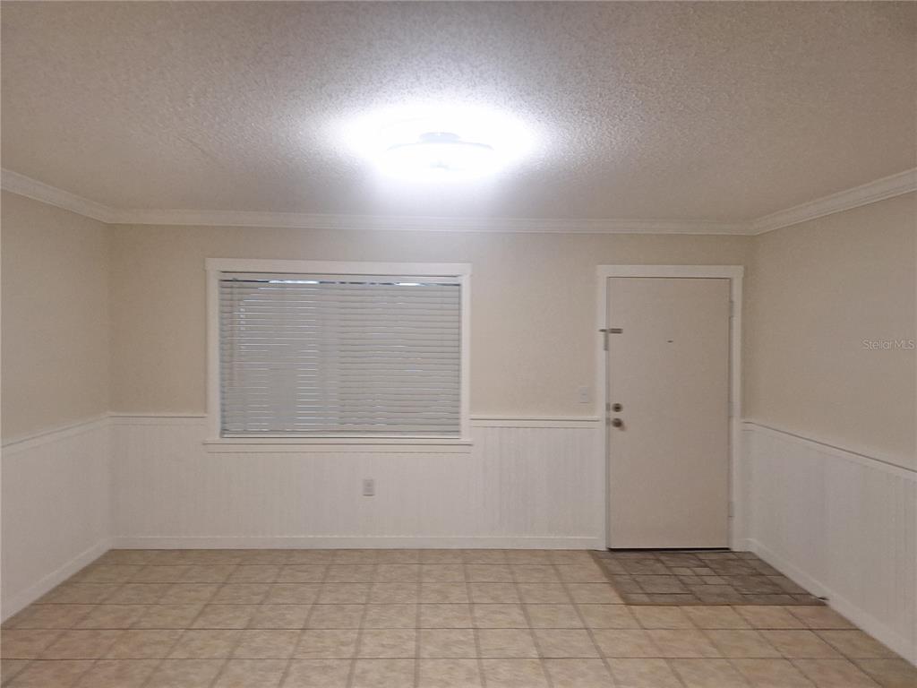 An interior room features beige walls with white wainscoting, tile flooring, a window, and a door — 136 BLUE POINTE WAY UNIT 350, ALTAMONTE SPRINGS, FL