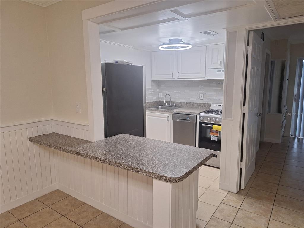 A kitchen with white cabinets, stainless steel appliances, and a breakfast bar with speckled countertops — 136 BLUE POINTE WAY UNIT 350, ALTAMONTE SPRINGS, FL