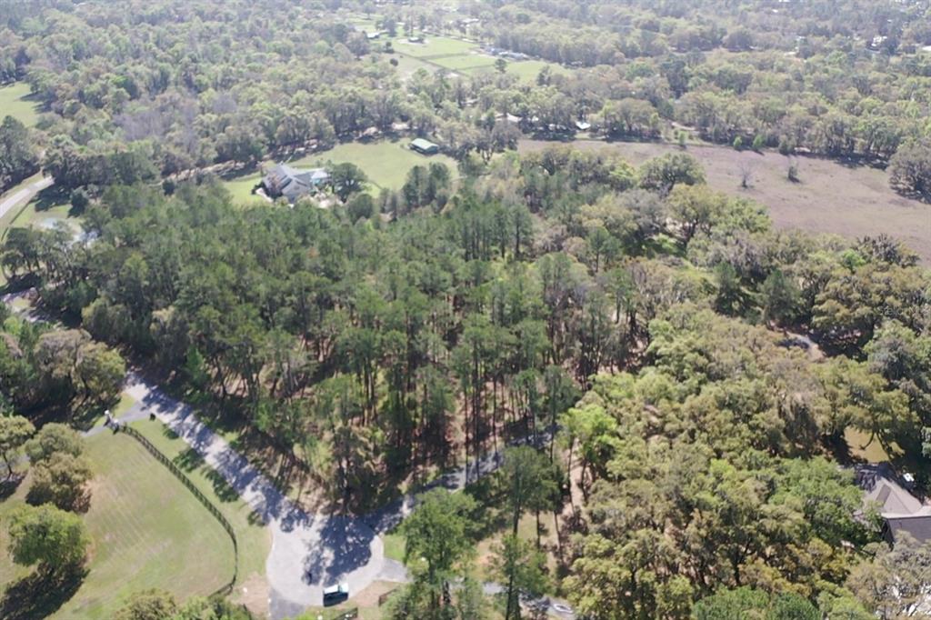 An aerial view shows a wooded lot with a cul-de-sac and nearby residential properties — 11 SW 144TH COURT, OCALA, FL