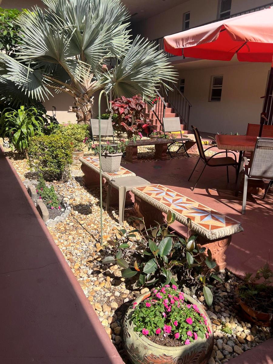 A patio area features tiled benches, potted plants, a palm tree, and outdoor dining furniture — 504 Davis Road # 95, Palm Springs FL 33461, PALM SPRINGS, FL