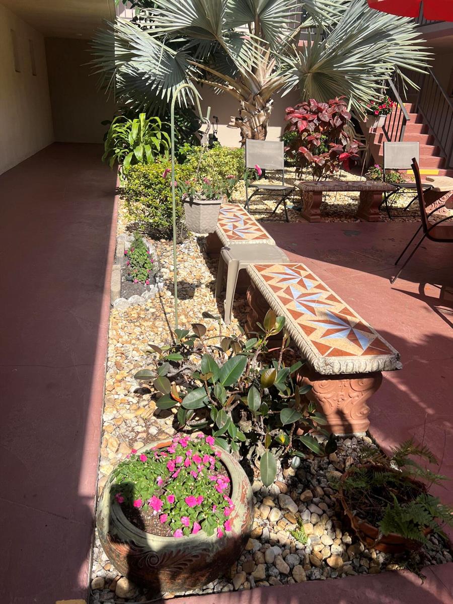A small outdoor courtyard features a tiled bench, potted plants, and a palm tree — 504 Davis Road # 95, Palm Springs FL 33461, PALM SPRINGS, FL