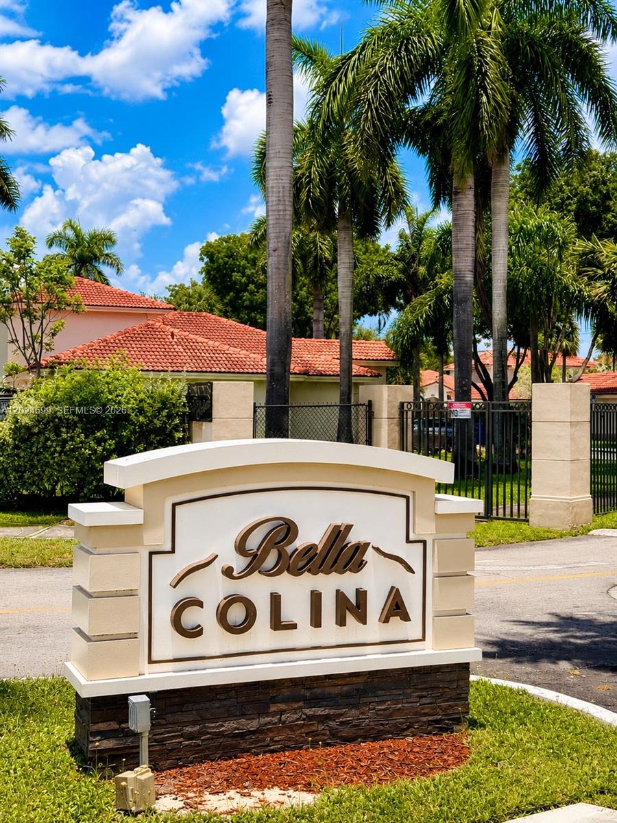 A beige monument sign for Bella Colina stands in front of palm trees and houses — 7305 NW 173rd Dr # 102, Hialeah FL 33015, HIALEAH, FL