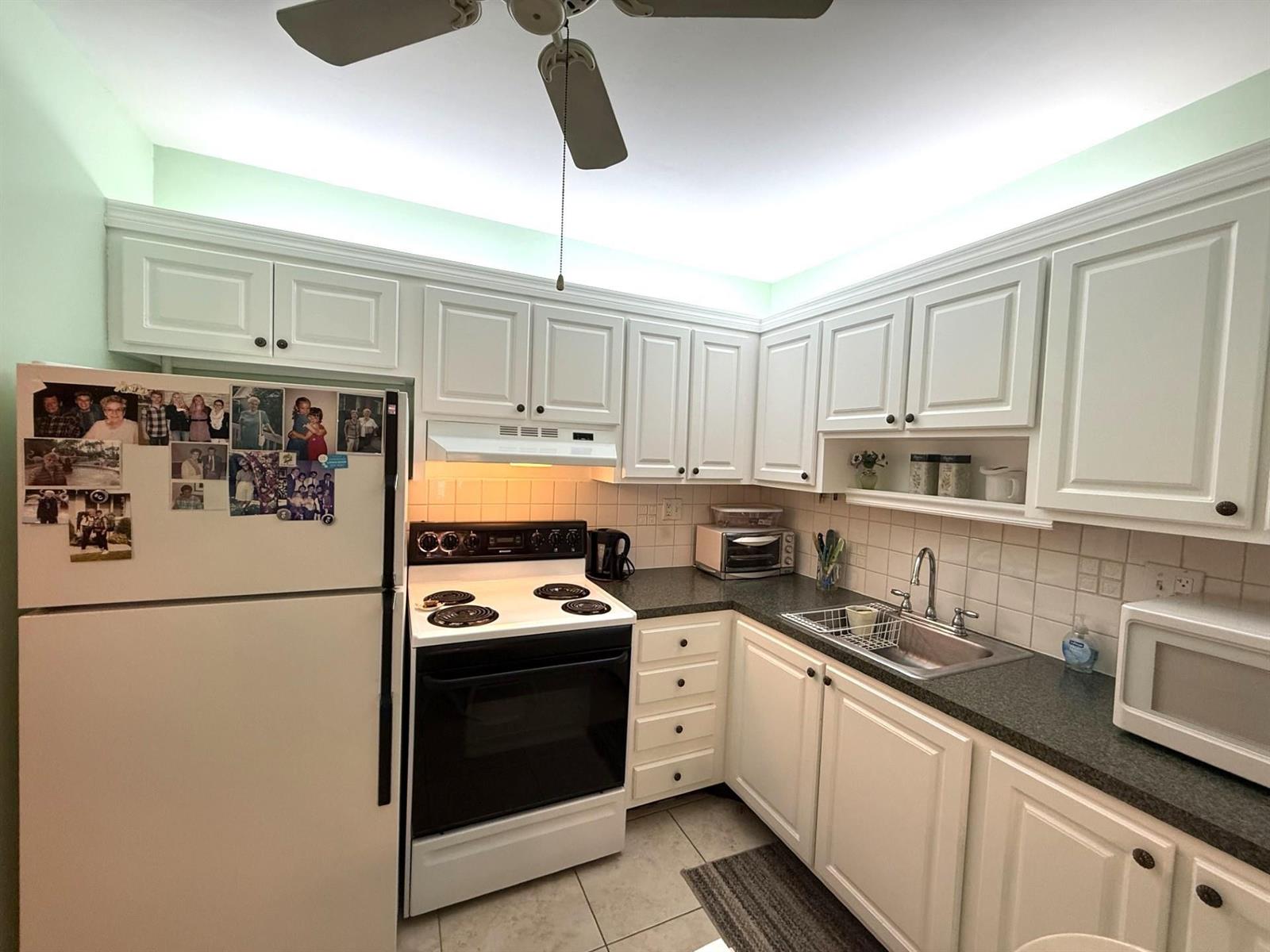 A kitchen features white cabinetry, a white stove, a refrigerator, and a stainless steel sink — 375 SW 56th Avenue # 116, Margate FL 33068, MARGATE, FL