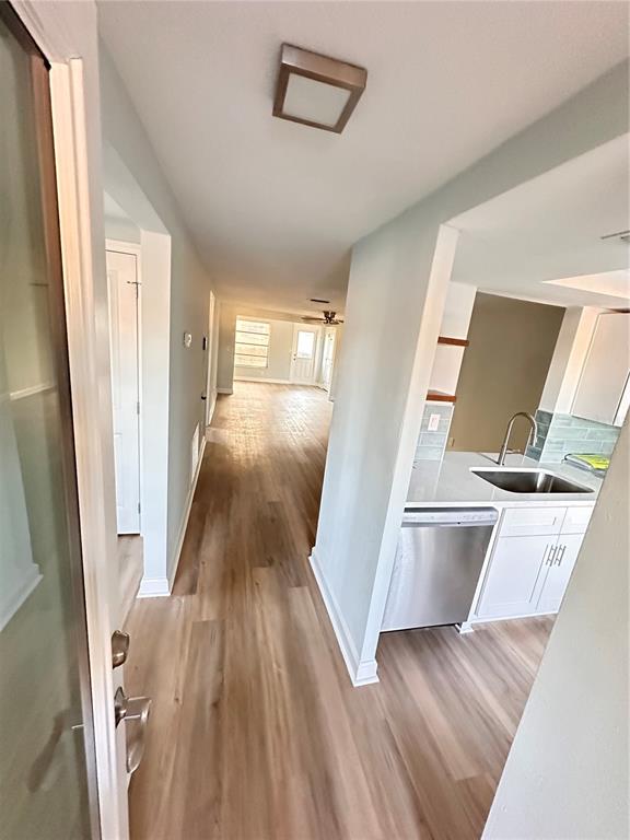 A view from a doorway looking into a kitchen with white cabinets and wood flooring — 4407 SUMMERSUN DRIVE, NEW PORT RICHEY, FL