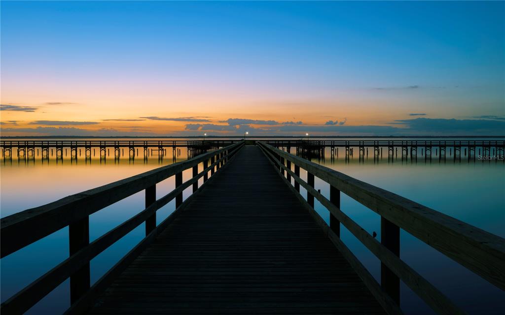 A wooden pier extends over calm water toward a sunset horizon under a clear sky — 824 ORCHID DRIVE, INDIAN LAKE ESTATES, FL
