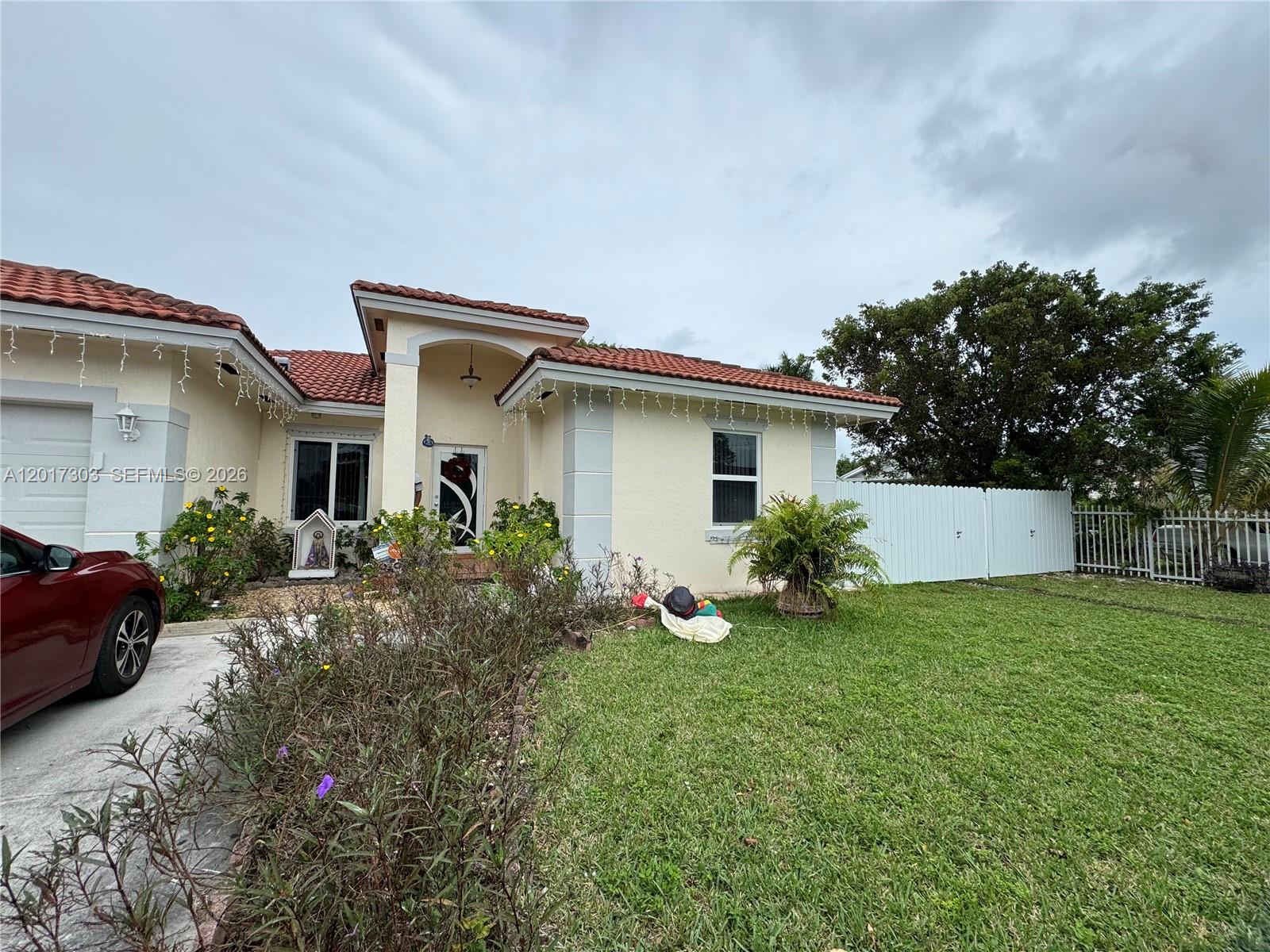 A single-story house with a red tile roof, beige stucco walls, and a white fence — 11951 SW 192nd Ter, Miami FL 33177, MIAMI, FL