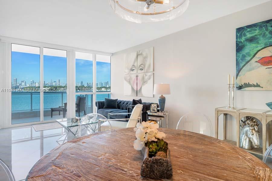 A bright living and dining area features a water view, modern furniture, and white walls — 540 West Ave # 411, Miami Beach FL 33139, MIAMI BEACH, FL