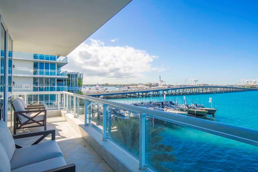 A balcony with outdoor seating overlooks a marina, a bridge, and the ocean — 540 West Ave # 411, Miami Beach FL 33139, MIAMI BEACH, FL